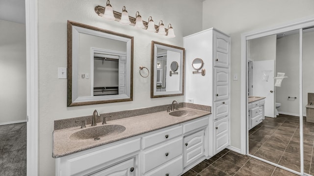 bathroom with double vanity, toilet, and a sink