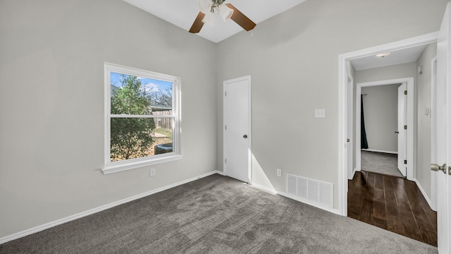 unfurnished bedroom featuring a ceiling fan, baseboards, visible vents, and dark colored carpet