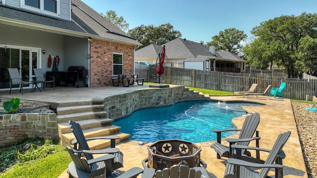 view of swimming pool featuring a fenced in pool, a patio, a fenced backyard, and an outdoor fire pit