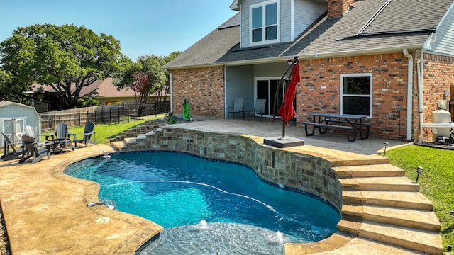 view of pool with a fire pit, fence, a shed, an outdoor structure, and a patio area