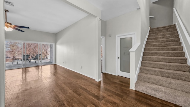 unfurnished living room with stairs, visible vents, baseboards, and wood finished floors