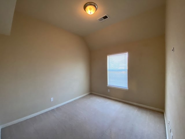 carpeted spare room with vaulted ceiling