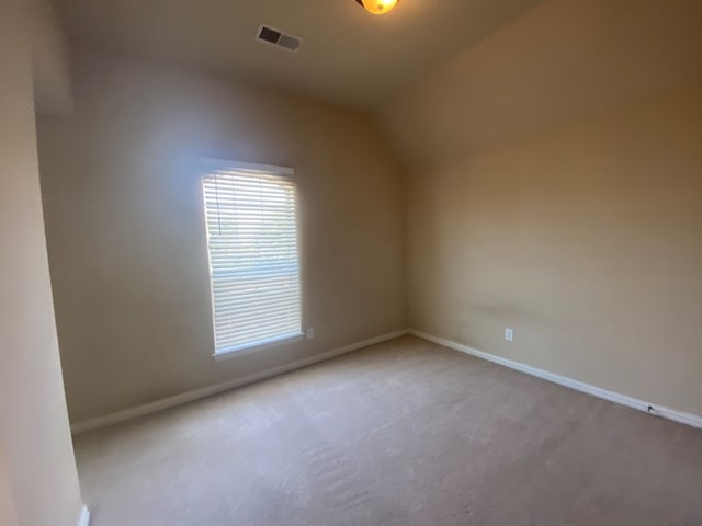 carpeted empty room featuring lofted ceiling