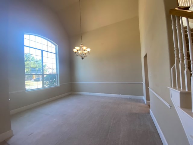 spare room featuring high vaulted ceiling, a notable chandelier, and carpet