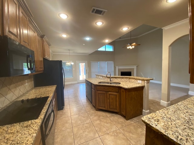 kitchen with an island with sink, black appliances, crown molding, and sink