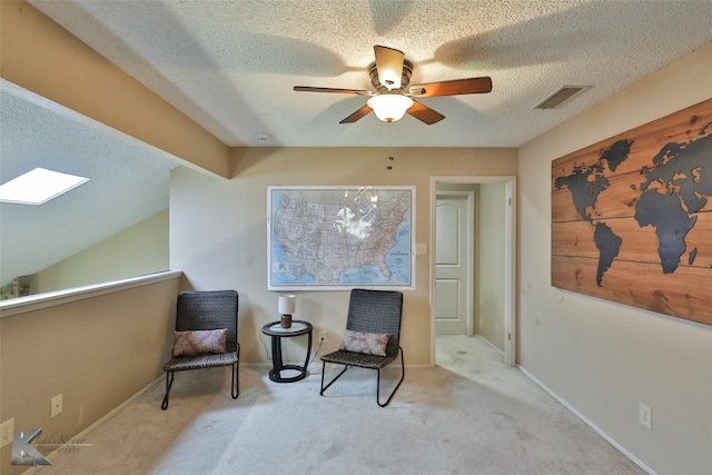 living area featuring light carpet, a textured ceiling, and ceiling fan