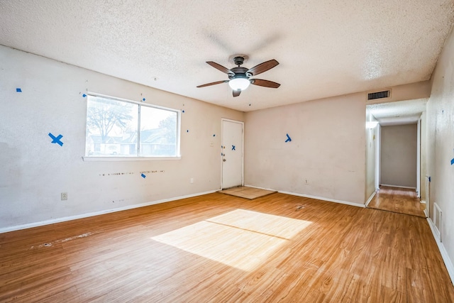 empty room with a textured ceiling, ceiling fan, and hardwood / wood-style flooring