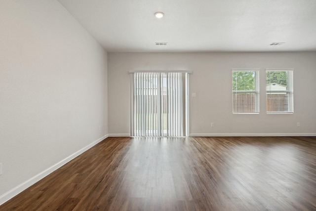 unfurnished room with baseboards, dark wood-style flooring, and visible vents