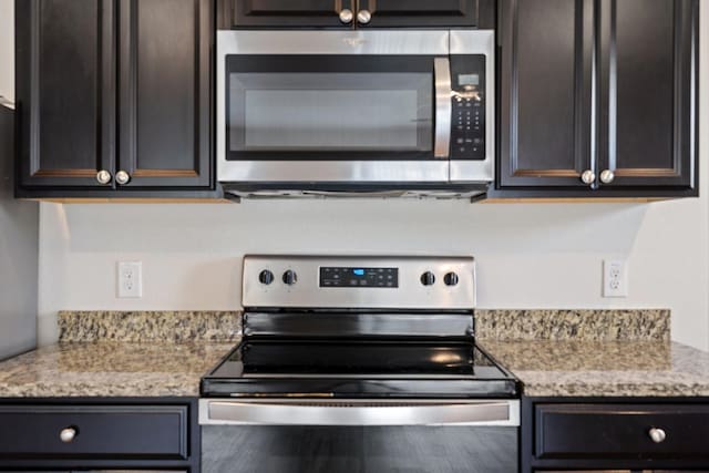 kitchen with light stone counters, appliances with stainless steel finishes, and dark brown cabinetry