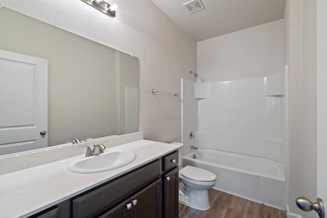 full bathroom featuring washtub / shower combination, hardwood / wood-style floors, vanity, and toilet