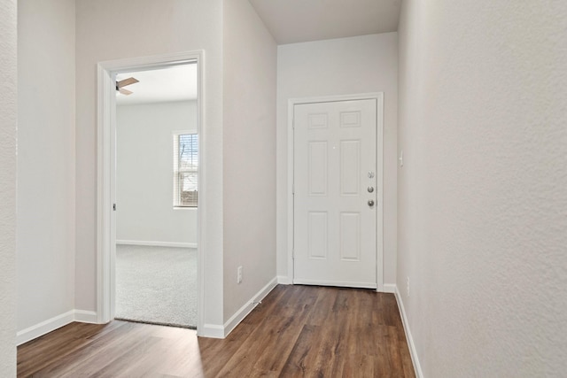 corridor featuring dark wood-type flooring and baseboards