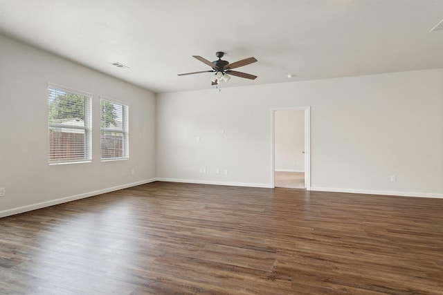 unfurnished room with visible vents, dark wood-style flooring, ceiling fan, and baseboards