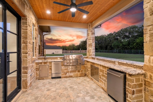 patio terrace at dusk with sink, exterior kitchen, area for grilling, and ceiling fan