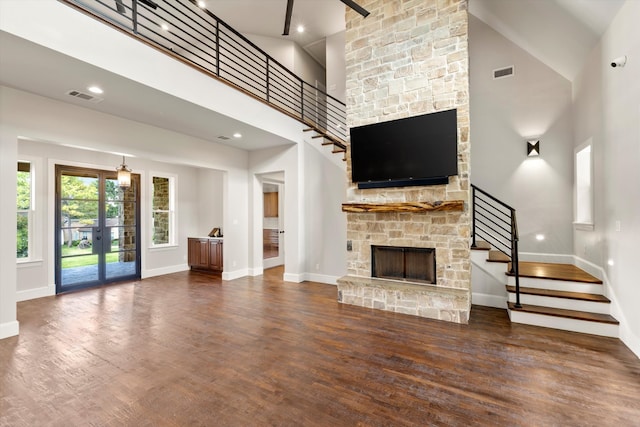 unfurnished living room with a high ceiling, dark wood-type flooring, a fireplace, and french doors