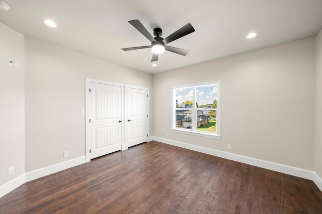 unfurnished bedroom with dark wood-type flooring, ceiling fan, and two closets