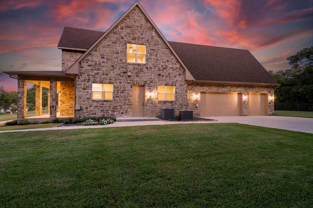 view of front of property featuring a yard, central AC, and a garage