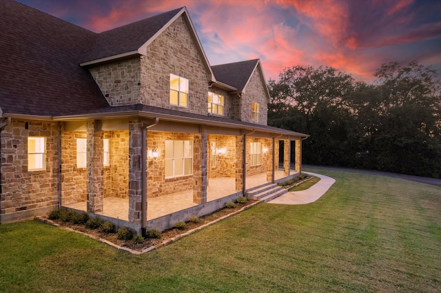 property exterior at dusk with a patio and a lawn