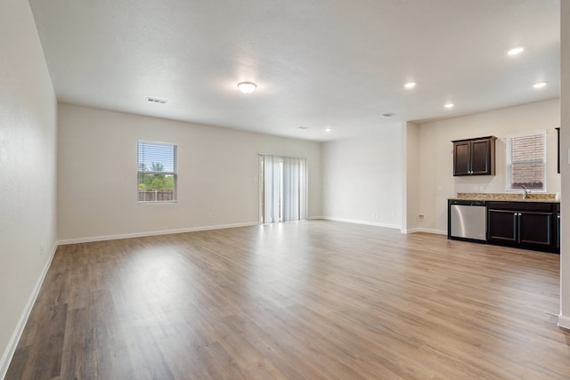 unfurnished living room featuring sink and light hardwood / wood-style flooring