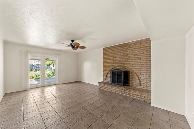 unfurnished living room with ceiling fan, dark tile patterned floors, french doors, a textured ceiling, and a fireplace