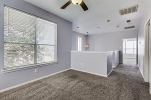 empty room featuring dark carpet and ceiling fan