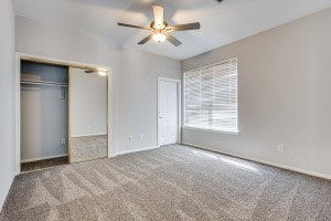 unfurnished bedroom with carpet floors, a closet, and ceiling fan