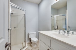 bathroom featuring vanity, toilet, and an enclosed shower