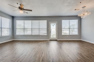 interior space with plenty of natural light, ceiling fan with notable chandelier, and dark hardwood / wood-style flooring