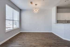 unfurnished dining area featuring a chandelier and dark hardwood / wood-style floors