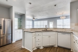 kitchen featuring a wealth of natural light, dishwasher, stainless steel refrigerator with ice dispenser, and white cabinetry