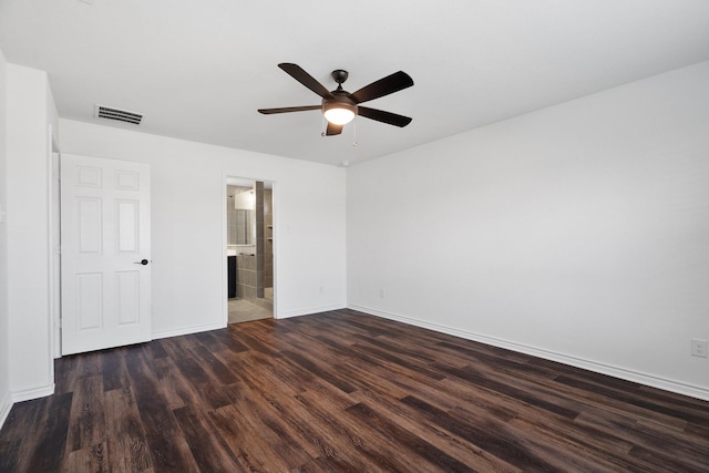 unfurnished bedroom featuring ceiling fan, dark wood-type flooring, and ensuite bath