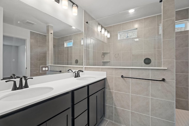 bathroom featuring tile patterned floors, vanity, tile walls, and tiled shower