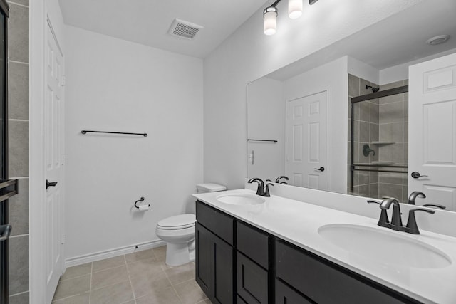 bathroom with toilet, vanity, tile patterned floors, and a shower with shower door