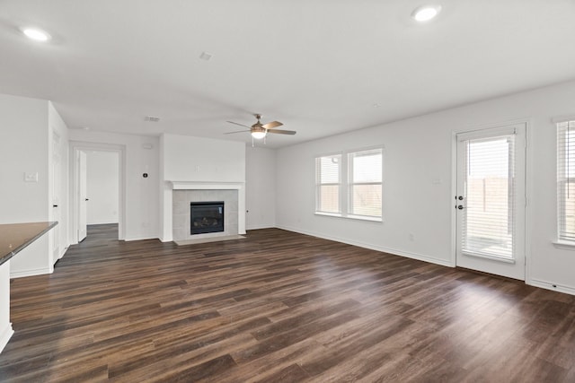 unfurnished living room featuring a tile fireplace, dark hardwood / wood-style floors, and ceiling fan