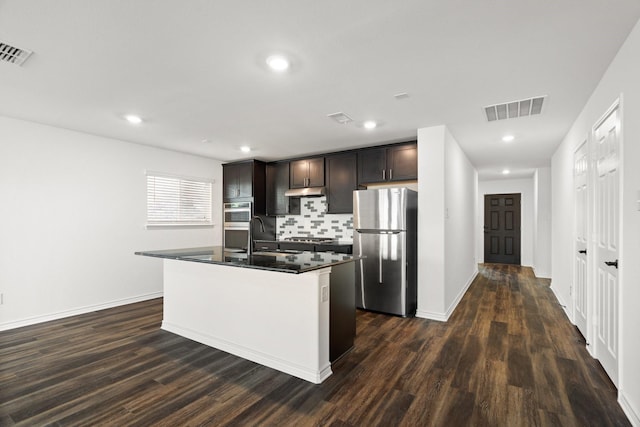 kitchen featuring tasteful backsplash, dark hardwood / wood-style floors, an island with sink, dark brown cabinets, and appliances with stainless steel finishes