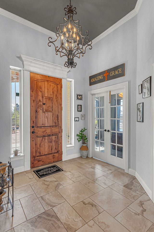 foyer entrance with crown molding, french doors, and a chandelier