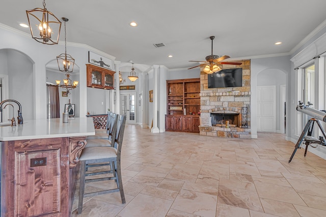 kitchen featuring pendant lighting, a fireplace, ornamental molding, and a kitchen breakfast bar