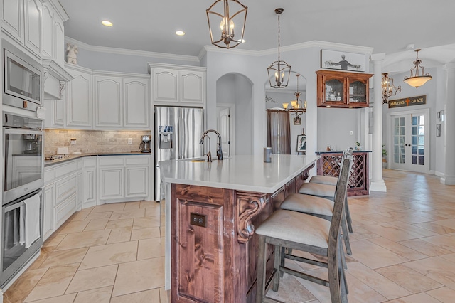 555 Mastadon Way, Weatherford, TX 76085 - kitchen with a chandelier, stainless steel appliances, decorative backsplash, ornamental molding, and an island with sink