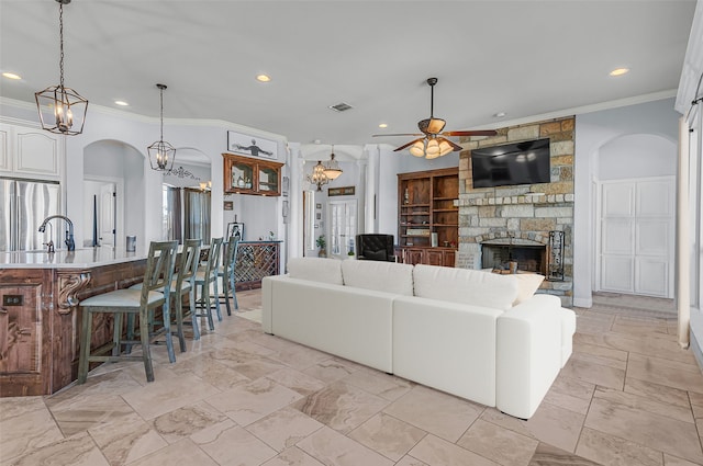 living room featuring ceiling fan, a fireplace, built in features, and ornamental molding