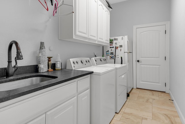 clothes washing area with washer and clothes dryer, sink, and cabinets