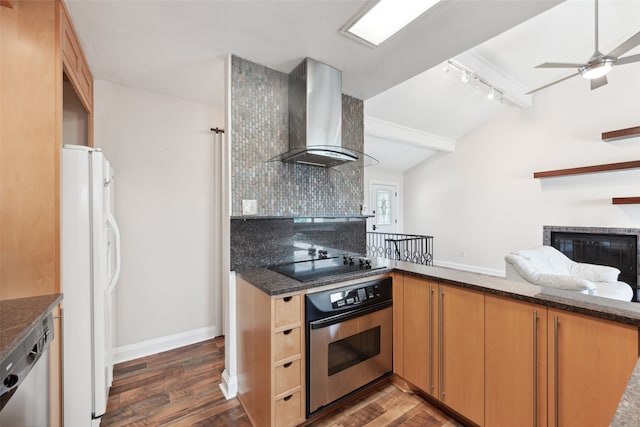 kitchen with wall chimney exhaust hood, dark hardwood / wood-style floors, backsplash, track lighting, and appliances with stainless steel finishes