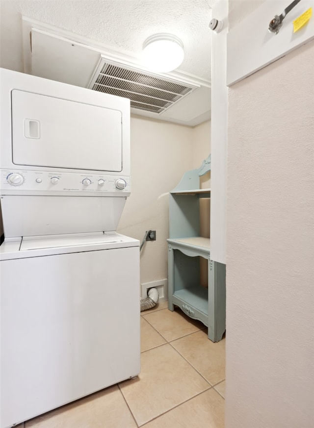 laundry room featuring light tile patterned floors and stacked washer / dryer