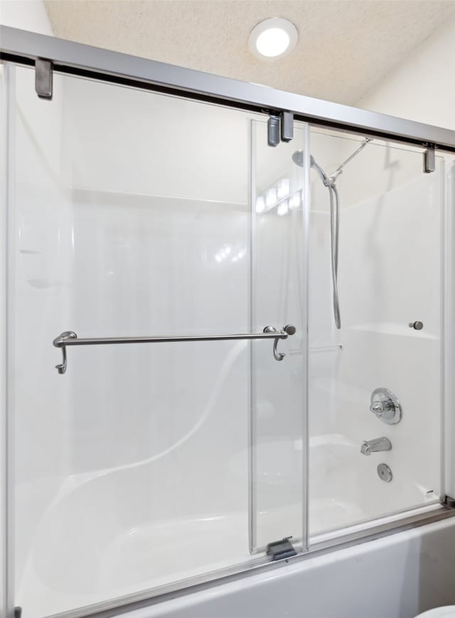 bathroom with shower / bath combination with glass door and a textured ceiling