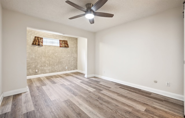 spare room featuring a barn door, ceiling fan, light hardwood / wood-style flooring, and a textured ceiling