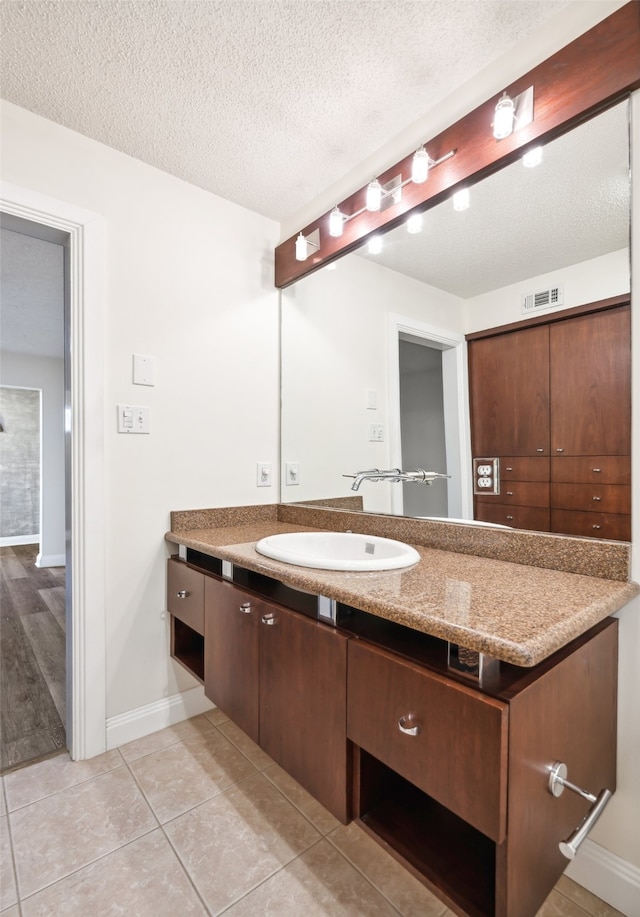 bathroom with vanity, a textured ceiling, and tile patterned floors