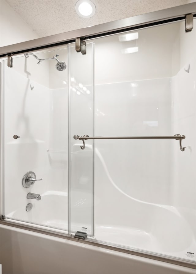 bathroom featuring enclosed tub / shower combo and a textured ceiling