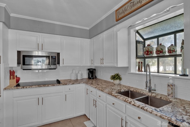 kitchen featuring light stone countertops, black electric stovetop, sink, white cabinetry, and light tile patterned flooring