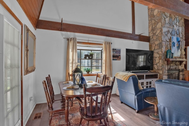 dining space with a fireplace, light hardwood / wood-style floors, and high vaulted ceiling