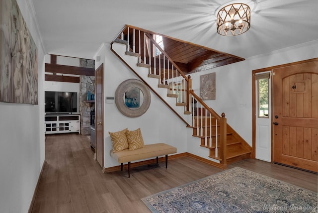 foyer entrance featuring crown molding, wood-type flooring, and an inviting chandelier