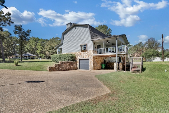 exterior space with a lawn, ceiling fan, a garage, and a wooden deck