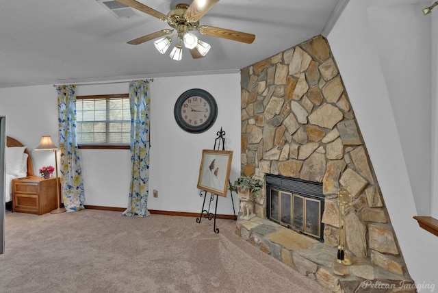 carpeted living room with a stone fireplace and ceiling fan